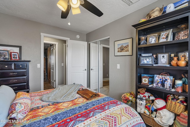 bedroom with a closet, a textured ceiling, a textured wall, and a ceiling fan