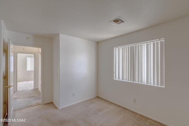 spare room with light carpet, baseboards, and visible vents