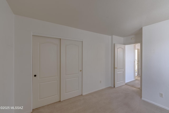 unfurnished bedroom with carpet flooring, baseboards, and a closet