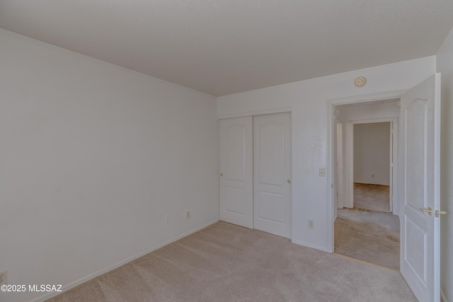 unfurnished bedroom with light carpet, baseboards, and a closet