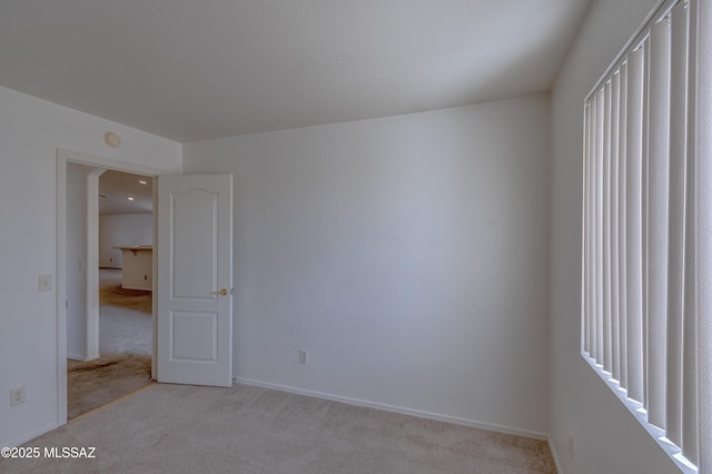 unfurnished bedroom featuring light colored carpet and baseboards