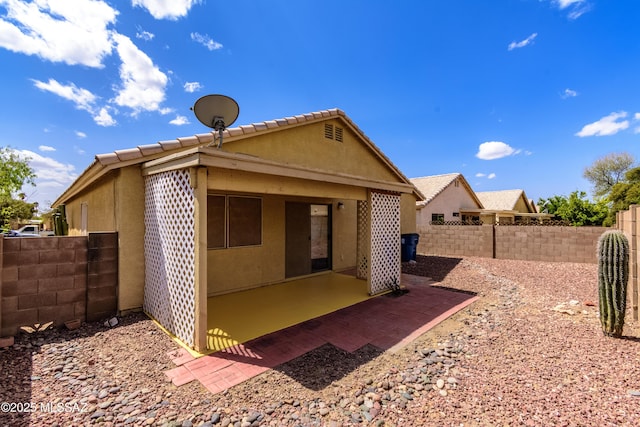 rear view of property with a tiled roof, stucco siding, fence, and a patio