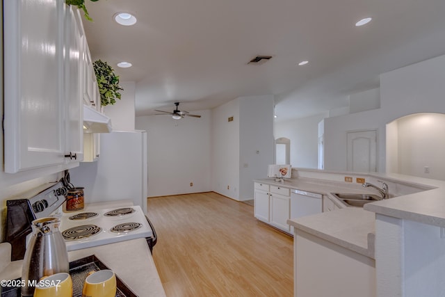 kitchen featuring a sink, under cabinet range hood, white appliances, visible vents, and arched walkways