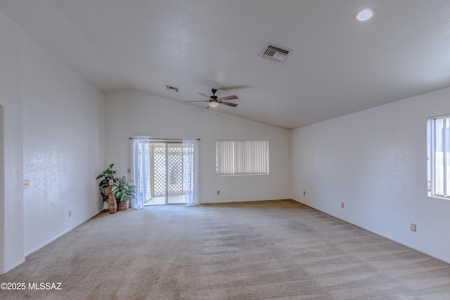 spare room featuring light carpet, visible vents, ceiling fan, and vaulted ceiling