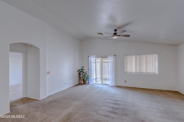 carpeted spare room featuring a ceiling fan, arched walkways, vaulted ceiling, and visible vents