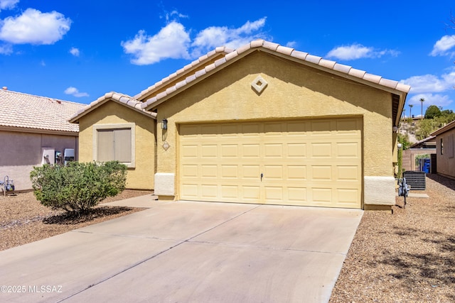 ranch-style home with cooling unit, stucco siding, an attached garage, a tiled roof, and driveway