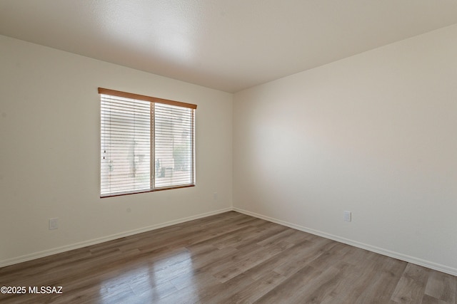 unfurnished room featuring baseboards and wood finished floors
