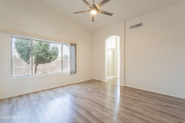 empty room featuring visible vents, light wood finished floors, baseboards, a ceiling fan, and arched walkways