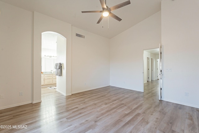 empty room with a ceiling fan, arched walkways, light wood finished floors, and visible vents