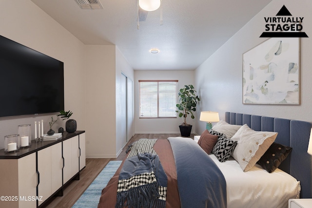 bedroom featuring baseboards, visible vents, and wood finished floors