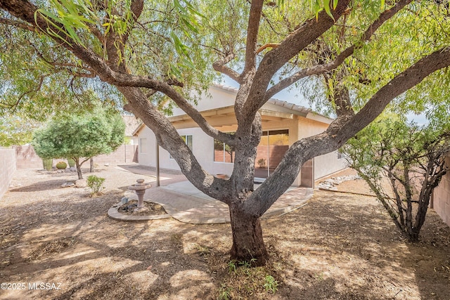 view of front of property with stucco siding, a fenced backyard, a patio, and a tiled roof