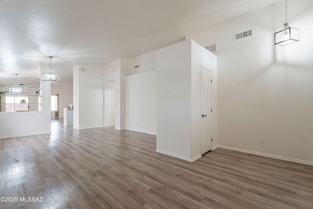 unfurnished living room with baseboards, visible vents, and wood finished floors