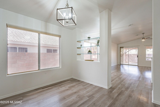 unfurnished dining area featuring visible vents, baseboards, wood finished floors, ceiling fan with notable chandelier, and vaulted ceiling