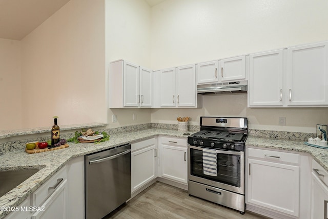 kitchen with white cabinetry, stainless steel appliances, under cabinet range hood, and light wood finished floors