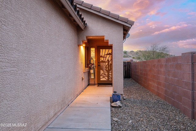 61080 Halter Pl, Saddlebrooke, AZ 85739 - exterior entry at dusk with stucco siding and fence