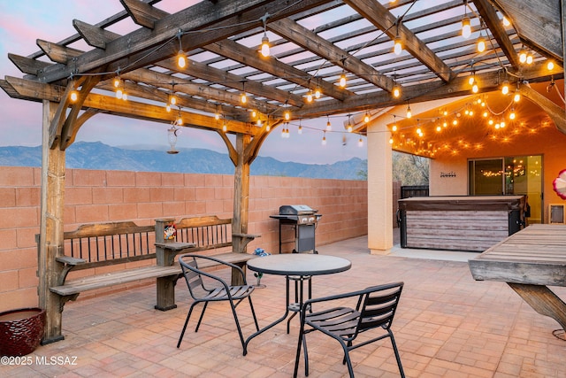 61080 Halter Pl, Saddlebrooke, AZ 85739 - patio terrace at dusk featuring area for grilling, fence, a hot tub, a pergola, and a mountain view