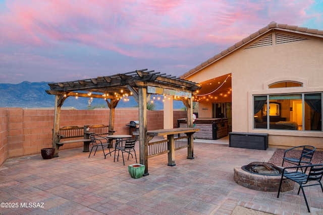 61080 Halter Pl, Saddlebrooke, AZ 85739 - patio terrace at dusk with a fire pit, a pergola, a mountain view, and fence