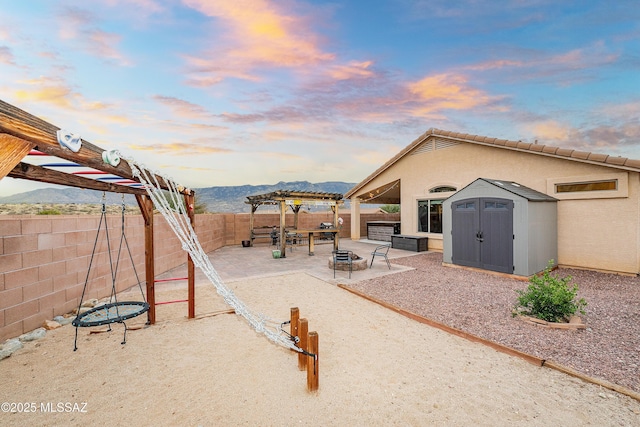 61080 Halter Pl, Saddlebrooke, AZ 85739 - view of patio featuring a fenced backyard, a fire pit, an outdoor structure, a pergola, and a shed