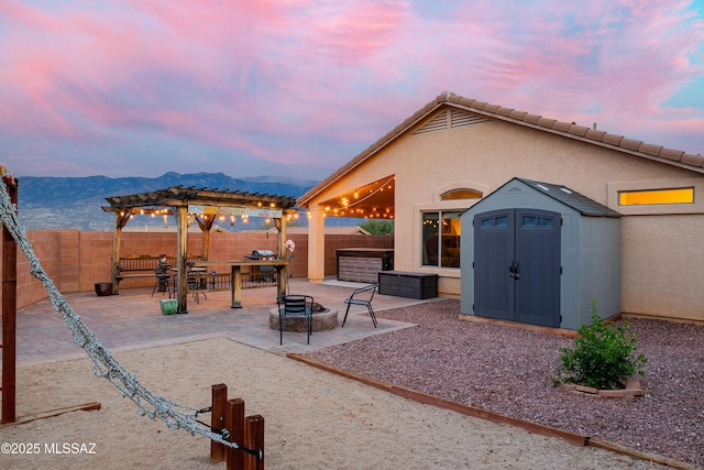 61080 Halter Pl, Saddlebrooke, AZ 85739 - view of patio / terrace with an outdoor structure, a fenced backyard, a storage unit, an outdoor fire pit, and a pergola