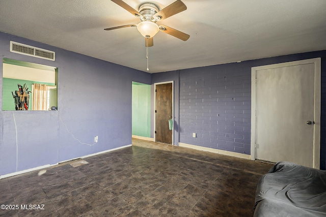 interior space with baseboards, visible vents, ceiling fan, and a textured ceiling