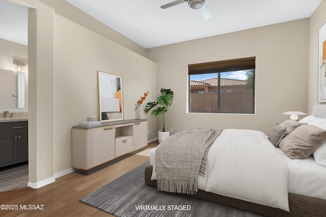 bedroom with wood finished floors, a sink, connected bathroom, ceiling fan, and baseboards
