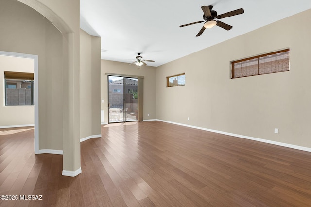 unfurnished room featuring a ceiling fan, baseboards, and dark wood-style flooring