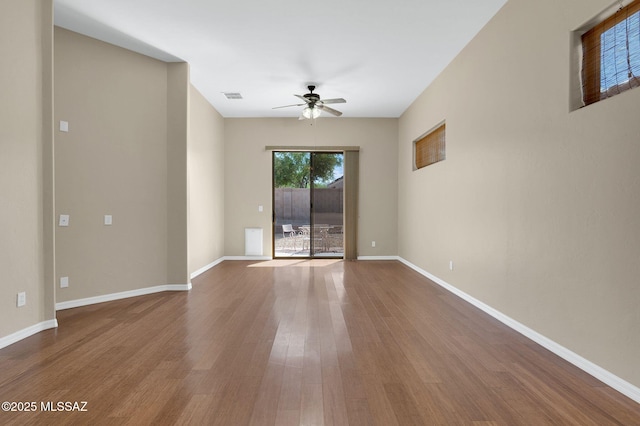 spare room with wood finished floors, baseboards, a ceiling fan, and visible vents