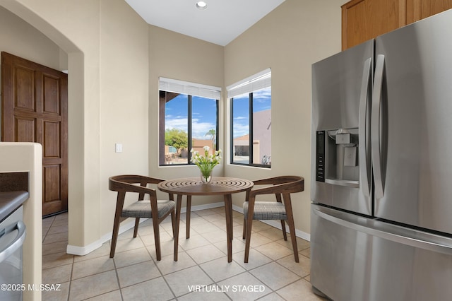 kitchen with arched walkways, stainless steel fridge, baseboards, recessed lighting, and light tile patterned floors
