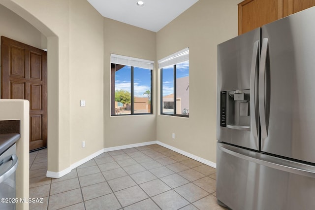 kitchen featuring recessed lighting, stainless steel fridge with ice dispenser, arched walkways, light tile patterned flooring, and baseboards