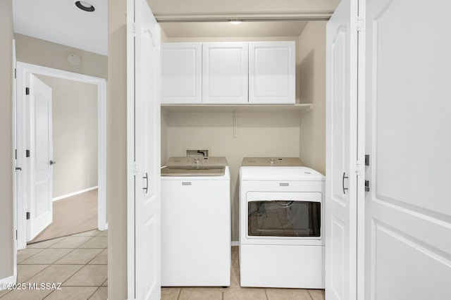 laundry area featuring baseboards, cabinet space, washer and clothes dryer, and light tile patterned floors