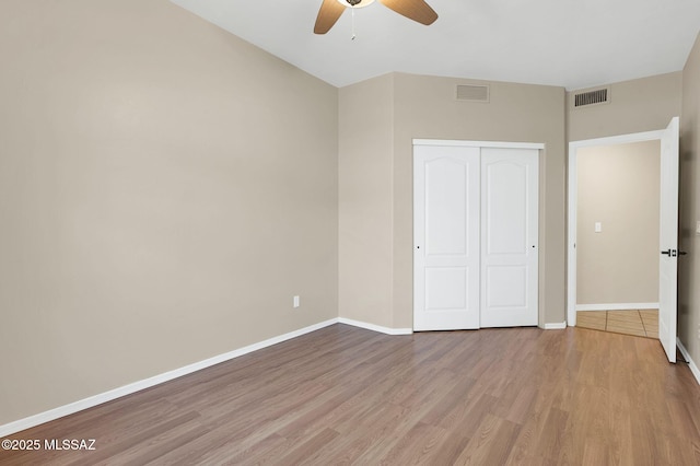 unfurnished bedroom with baseboards, wood finished floors, visible vents, and a closet