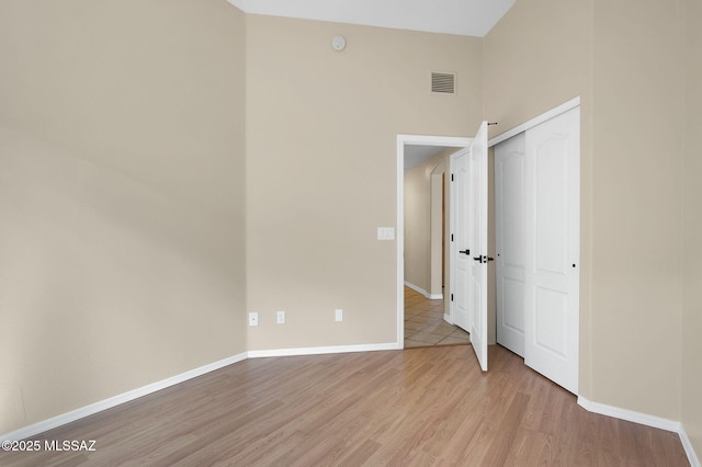unfurnished bedroom with baseboards, a closet, visible vents, and light wood-style flooring