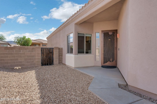 exterior space with stucco siding, a gate, and fence