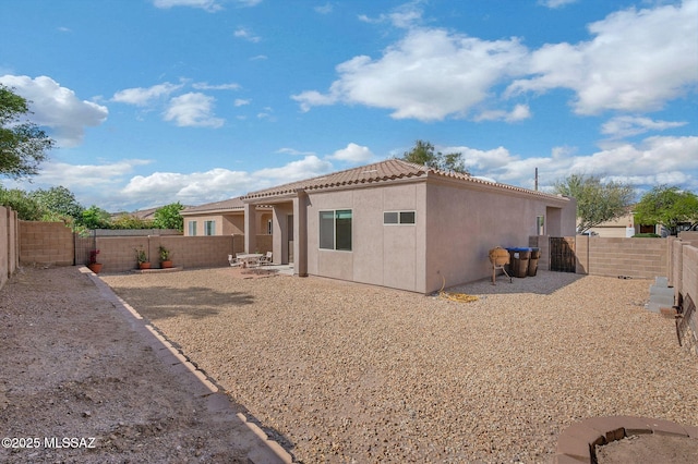 back of house featuring a tile roof, a fenced backyard, and stucco siding