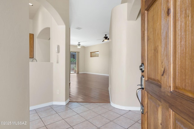 foyer entrance featuring visible vents, arched walkways, light tile patterned flooring, baseboards, and ceiling fan