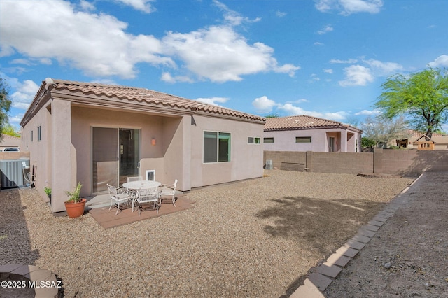 back of house with a fenced backyard, a tiled roof, central AC, stucco siding, and a patio