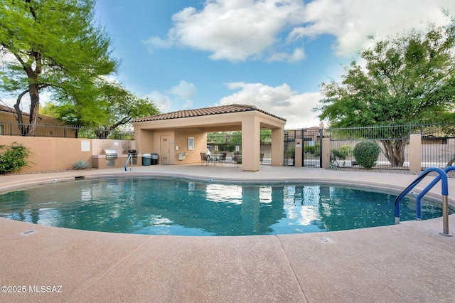 pool with fence, a patio area, and a grill