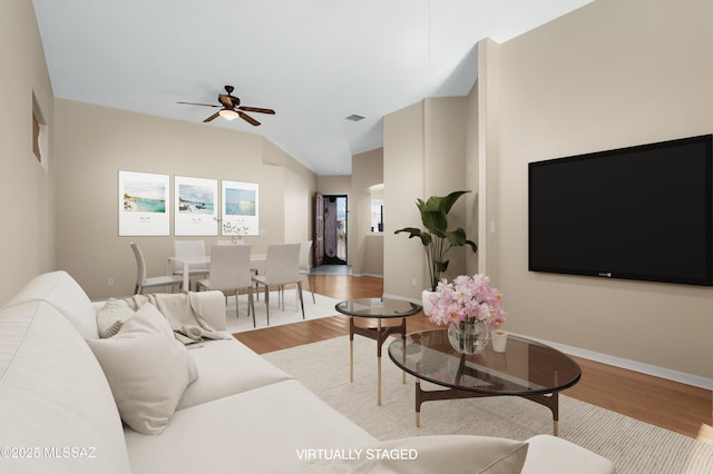 living room with vaulted ceiling, wood finished floors, visible vents, a ceiling fan, and baseboards