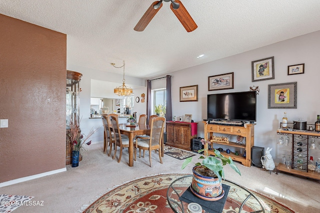 carpeted living room featuring baseboards, a textured ceiling, and ceiling fan with notable chandelier