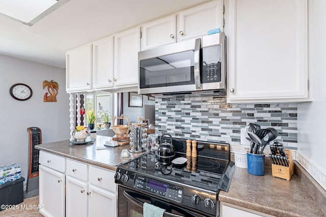 kitchen with stainless steel microwave, white cabinets, electric range, and decorative backsplash
