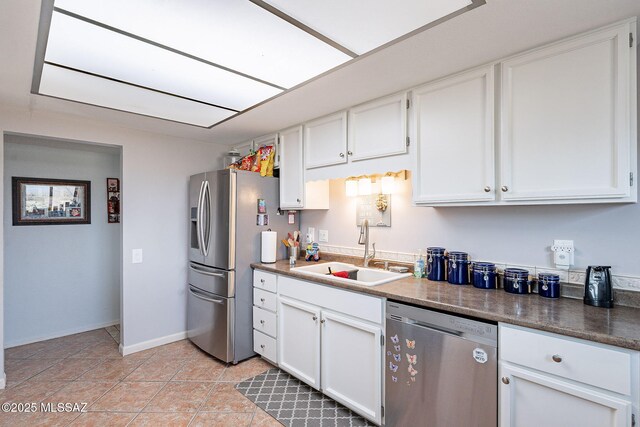 kitchen with light tile patterned floors, baseboards, a sink, white cabinets, and appliances with stainless steel finishes