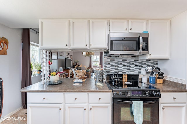 kitchen featuring white cabinetry, black range with electric cooktop, a peninsula, stainless steel microwave, and decorative backsplash