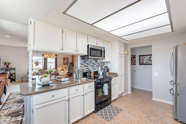 kitchen featuring light tile patterned flooring, backsplash, white cabinetry, appliances with stainless steel finishes, and a peninsula