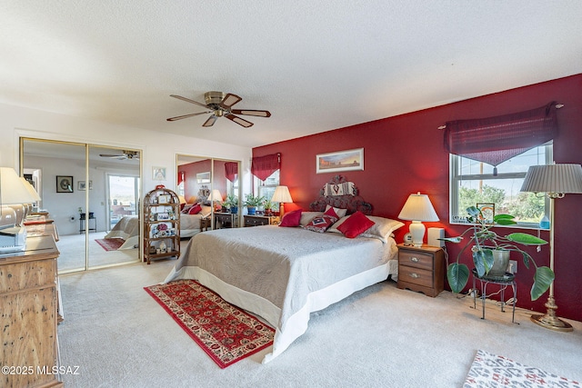 bedroom featuring multiple windows, ceiling fan, carpet flooring, and a textured ceiling