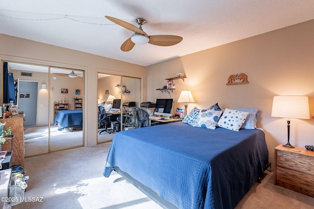 carpeted bedroom with visible vents, two closets, and a ceiling fan