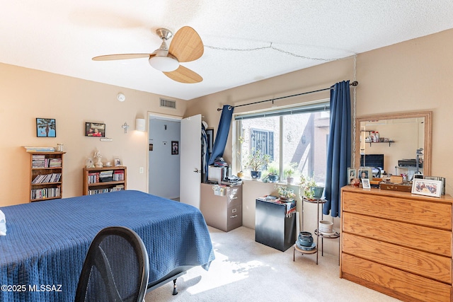 bedroom with a ceiling fan, a textured ceiling, light colored carpet, and visible vents