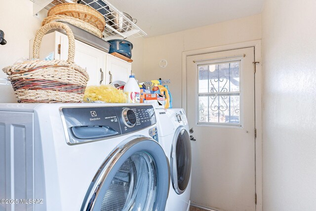 clothes washing area featuring cabinet space and washer and clothes dryer