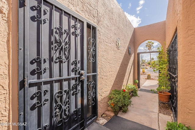 doorway to property featuring a gate and stucco siding