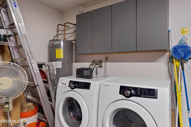 washroom with concrete block wall, washing machine and dryer, cabinet space, and electric water heater