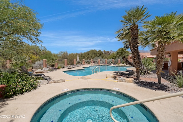 pool with fence, a hot tub, and a patio area